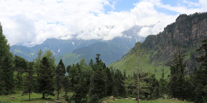 A breathtaking view of a lush green mountain range under dense white clouds during the day