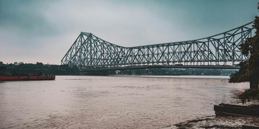 A breathtaking view of a black bridge on top of a water body during the daytime.