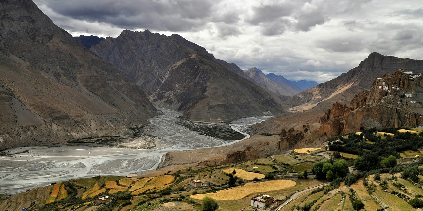 A breathtaking view of the Spiti Valley with enormous mountains and a stream of water.