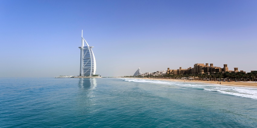 A stunning distant view of a hotel in Dubai surrounded by a water body during the day.