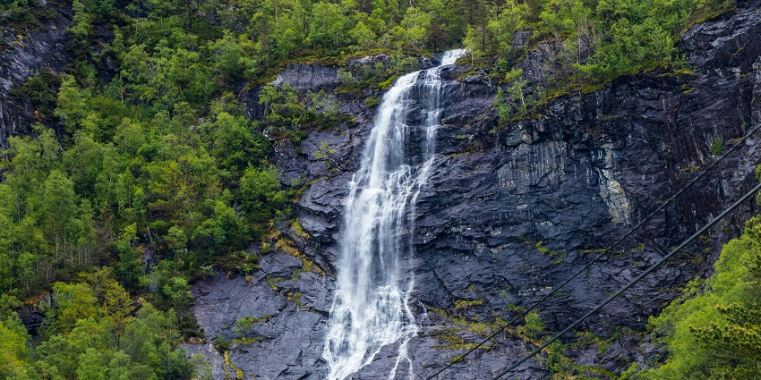 A mesmerising view of a waterfall cascading down the rocks around lush greenery.