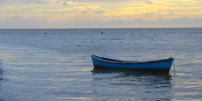 A breathtaking view of a boat in a body of water with the sun setting in the background.