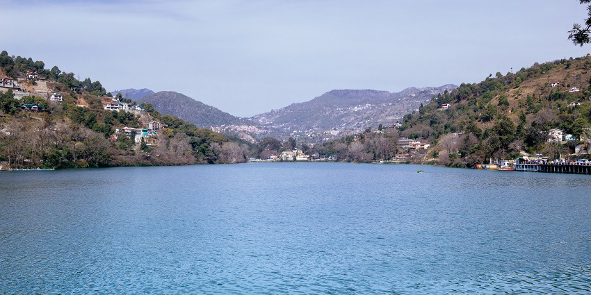 Scenic view of a lake surrounded by houses with forested hills in the background
