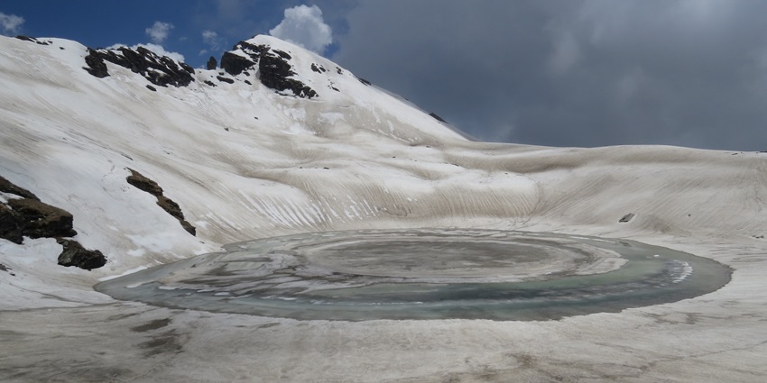 A picture of a majestic lake in Manali with giant snow-covered mountains all around