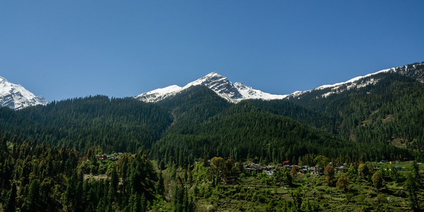 An image of the green mountain under a blue sky at Bhuntar, Barshaini, Himachal Pradesh.