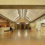 A picture of a museum's interiors showing a long hallway with people admiring art