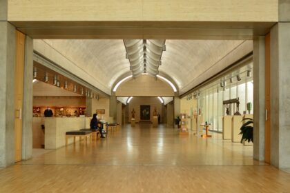 A picture of a museum's interiors showing a long hallway with people admiring art