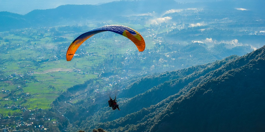An alluring view of a person paragliding in the valleys of Bir in Himachal Pradesh