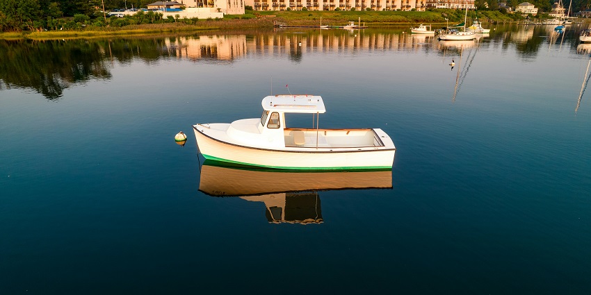 A scenic view of a boat in a water body with houses and clear skies in the background.