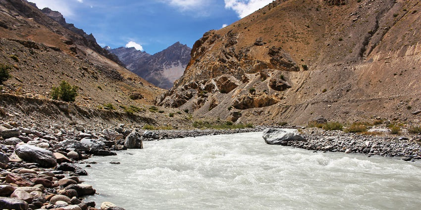 A scenic view of Bogamati featuring a frothy river, lofty mountains, and greenery.