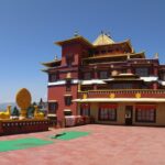 A day light photograph of Ngedon Chokhor Ling Monastery with carpets spread around.