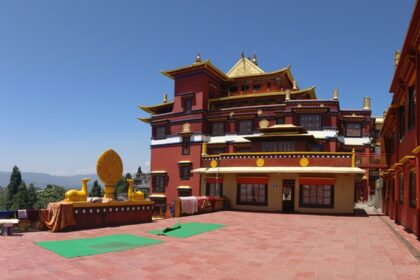 A day light photograph of Ngedon Chokhor Ling Monastery with carpets spread around.