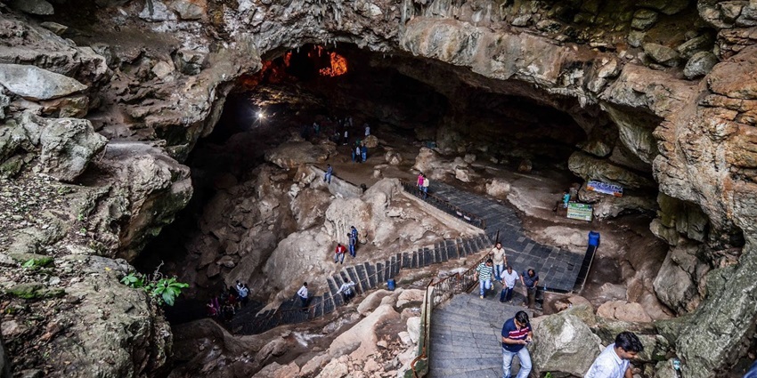 An aerial view of a staircase in the middle of a rocky terrain, leading to a cave