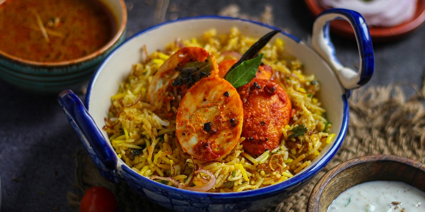 Blue ceramic bowl filled with aromatic biryani, garnished with herbs and spices.