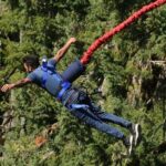 An image of a man jumping in the scenic backdrop of mountains and lush greenery.