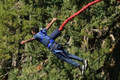 An image of a man jumping in the scenic backdrop of mountains and lush greenery.