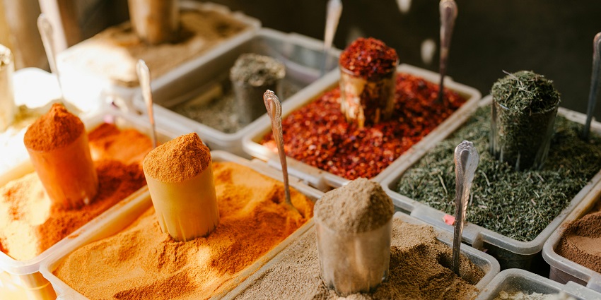 A close-up view of varied spices at a counter in a street shop during the daytime.