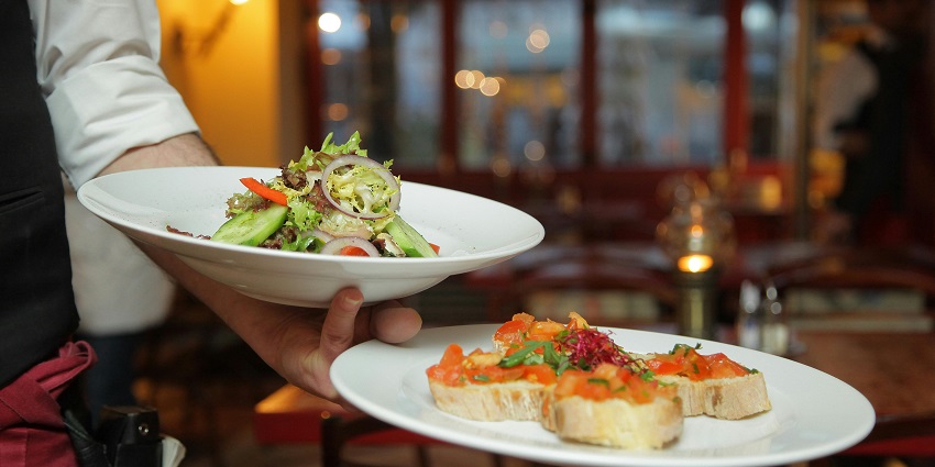 A picture of a waiter serving food at a restaurant