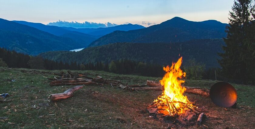 A stunning view of a bonfire in an open lush green grass field during the evening.