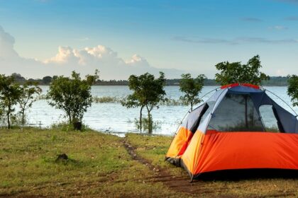 Camping tent in orange colour near lakeside - one of the best sites for camping in Shillong