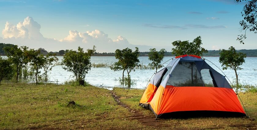 Camping tent in orange colour near lakeside - one of the best sites for camping in Shillong