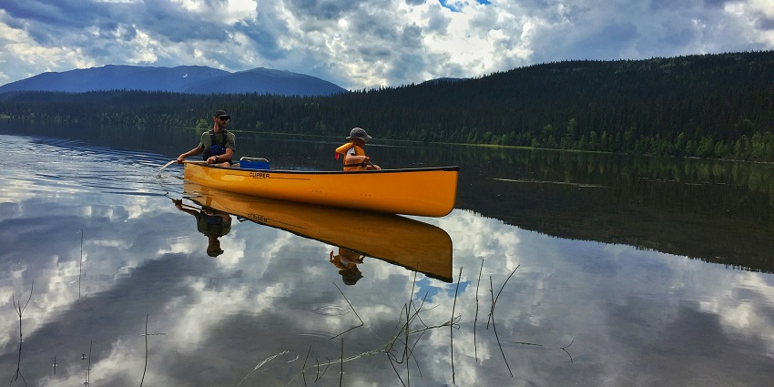 Two people in a canoe on a tranquil lake, enjoying a peaceful water activity.