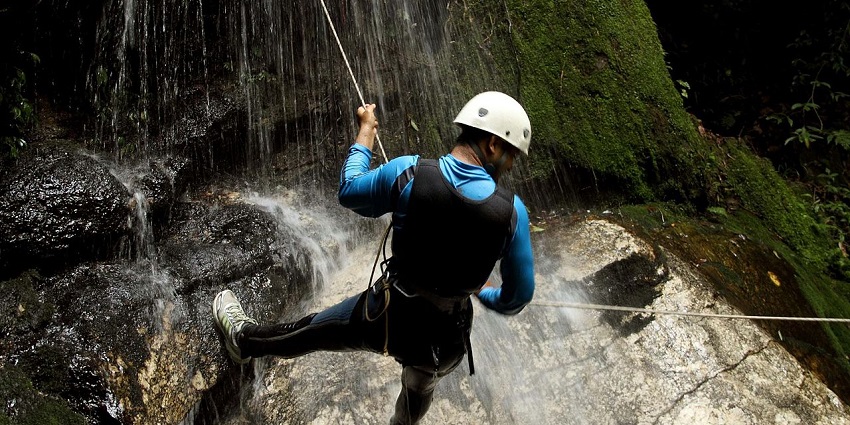 A man holding on to a rope that is used as a support while climbing mountains