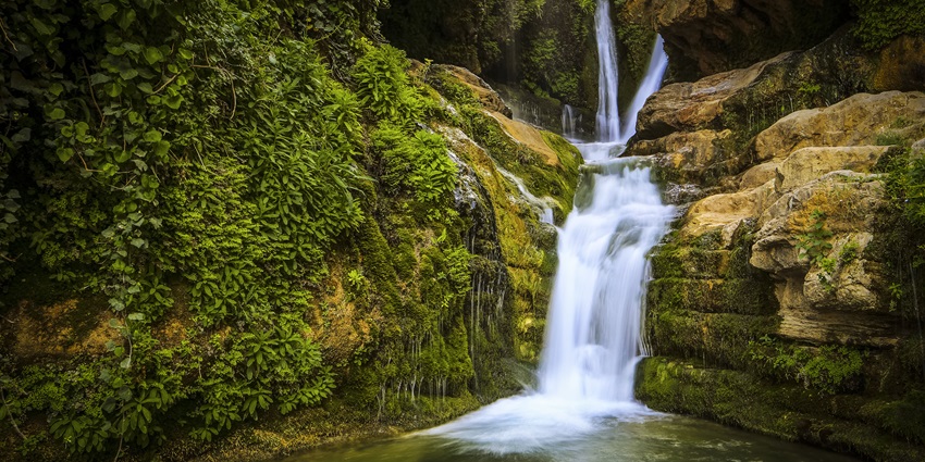 A picture of a scenic waterfall cascading through the verdant hills of Shimla