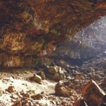 A breathtaking view of the inside of a cave with small and big rocks during the day.