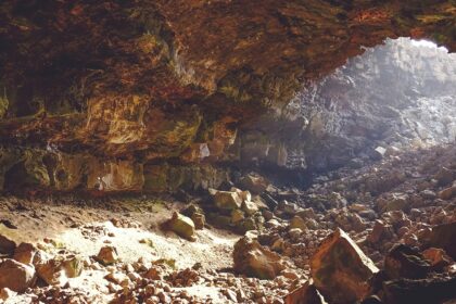 A breathtaking view of the inside of a cave with small and big rocks during the day.