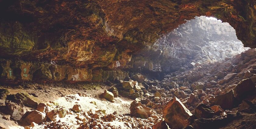 A breathtaking view of the inside of a cave with small and big rocks during the day.