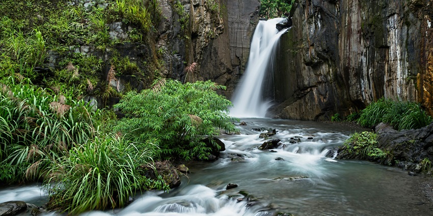 Cave waterfall with water cascading down from within a rocky cave, creating a serene.
