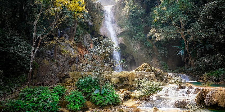 Silver waterfall cascading down the rocks amidst lush vegetation