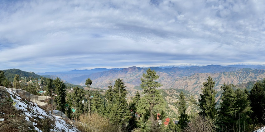 A panoramic view of mountains, lush green vegetation, and cloudy sky in Chail