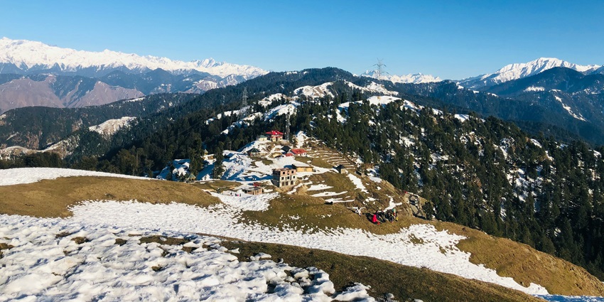 A serene view of Chamba, Uttarakhand featuring snow-capped mountains and lush greenery.