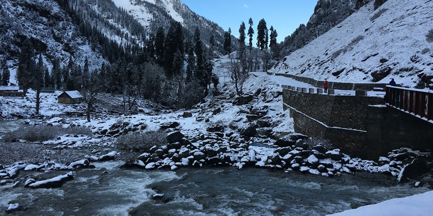 A picture of a scenic meadow in Pahalgam with snow-covered landscapes all around