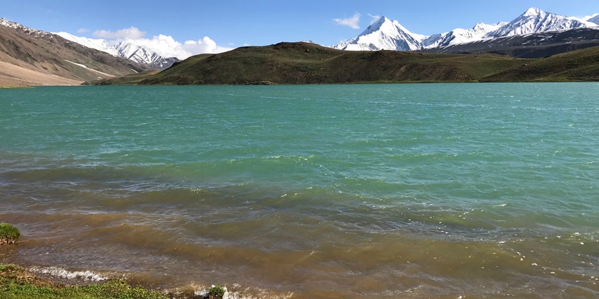 Chandra Taal Lake has crystal clear water, surrounded by towering mountains reaching the sky.