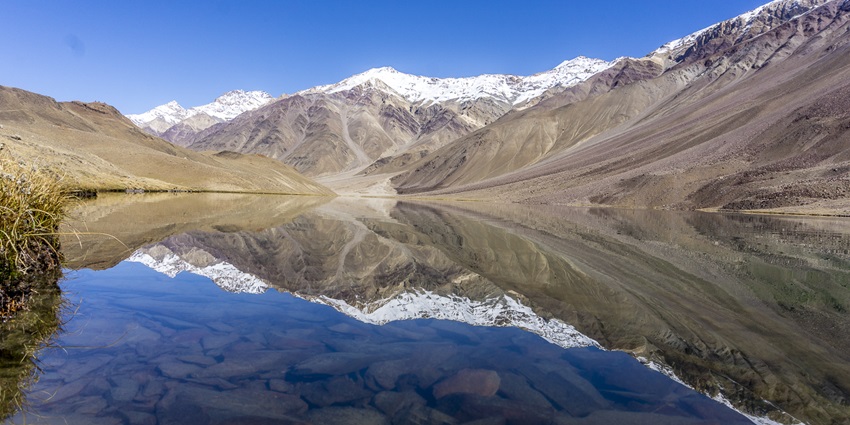 An astounding view of the Chandratal Lake with a backdrop of snow-clap mountain peaks.