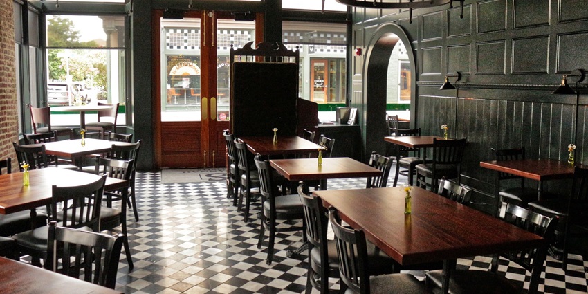 A picture of a restaurant from inside with a beautiful table setting and cutlery placed on top of the table