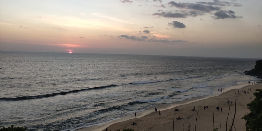 A picture of a beach near the Chandragiri Fort during sunset, with people relaxing by the shore