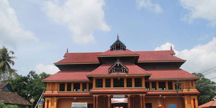 A frontal view of a traditional Hindu temple in Thiruvalla, with vehicles parked in the parking space