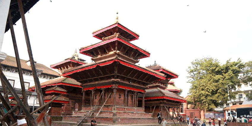A picture of a traditional Hindu temple with red walls and a flag on top of its roof