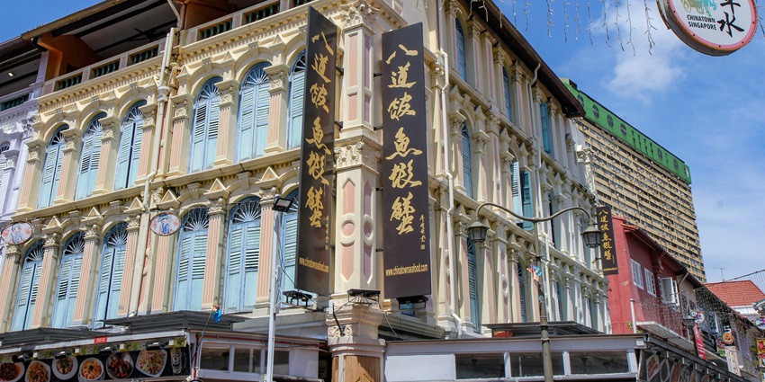 A mesmerising view of a brown concrete building with black banners during the daytime.