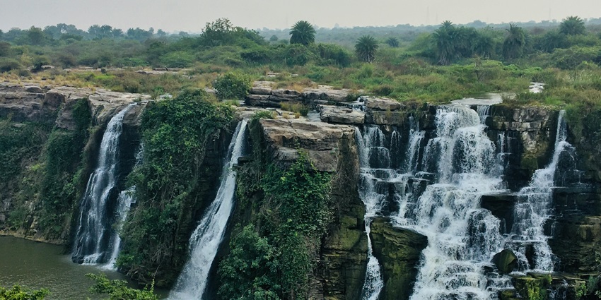 Waterfall cascading down a lush mountain slope into misty surroundings
