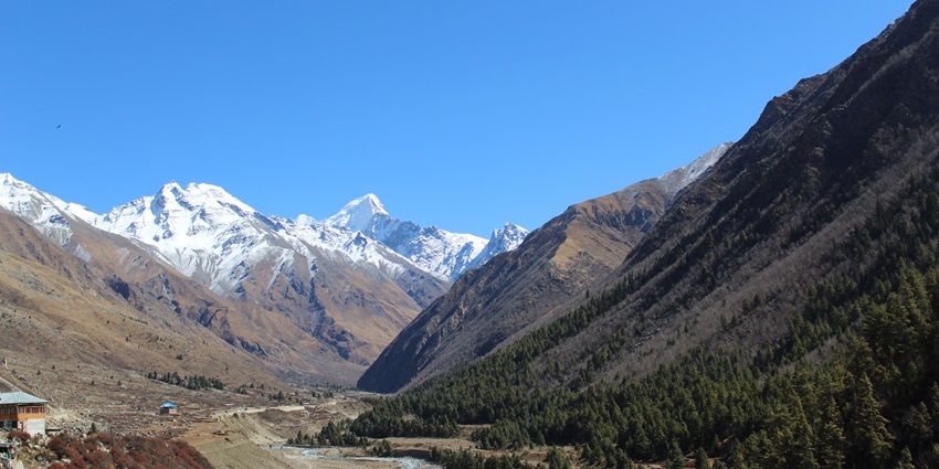 A picture of a river flowing through a valley, surrounded by tall mountains on all sides