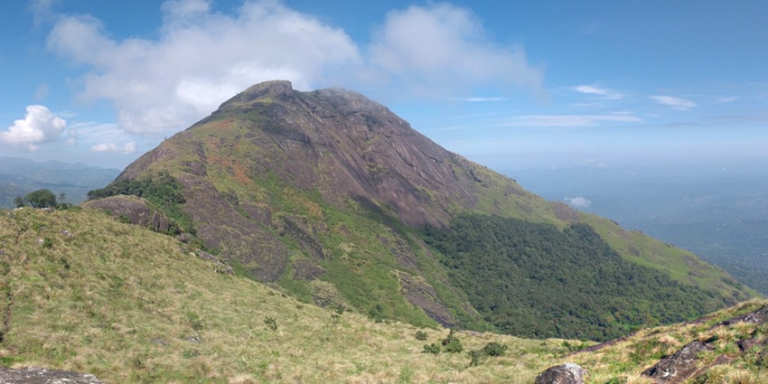 A scenic view of the Chokramudi Peak featuring towering peaks and lush greenery.