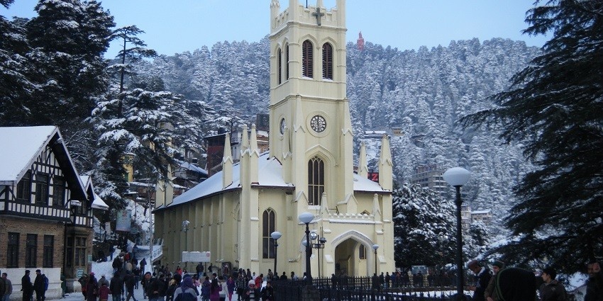 A church in Shimla during winter with a snow-capped mountain in the background