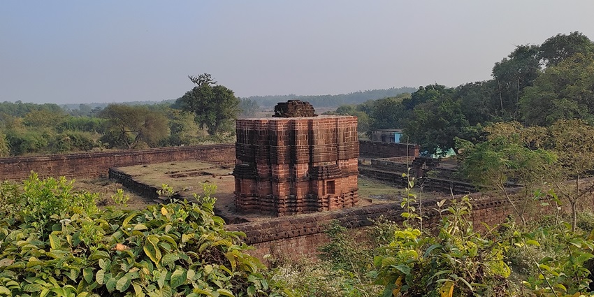Ruined red-stone Raibania Fort complex surrounded by greenery in Balasore, Odisha.