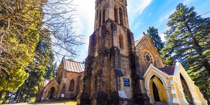 A picture of a historical church in Himachal Pradesh, surrounded by trees and forest