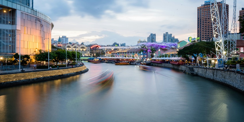 A breathtaking view of Clarke Quay with a body of water flowing through a vibrant city.